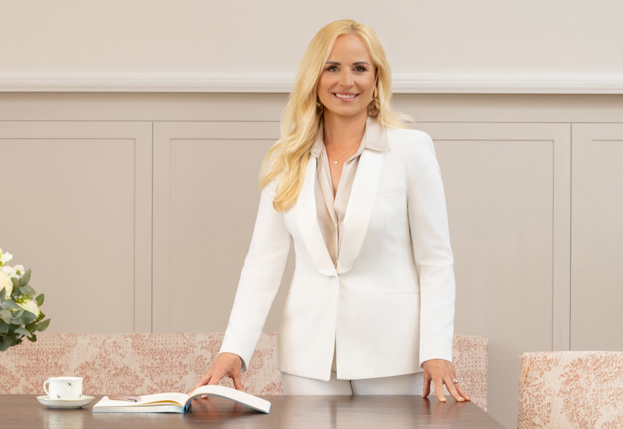 Selbstbewusste Frau in weißem Anzug bei Business-Meeting.