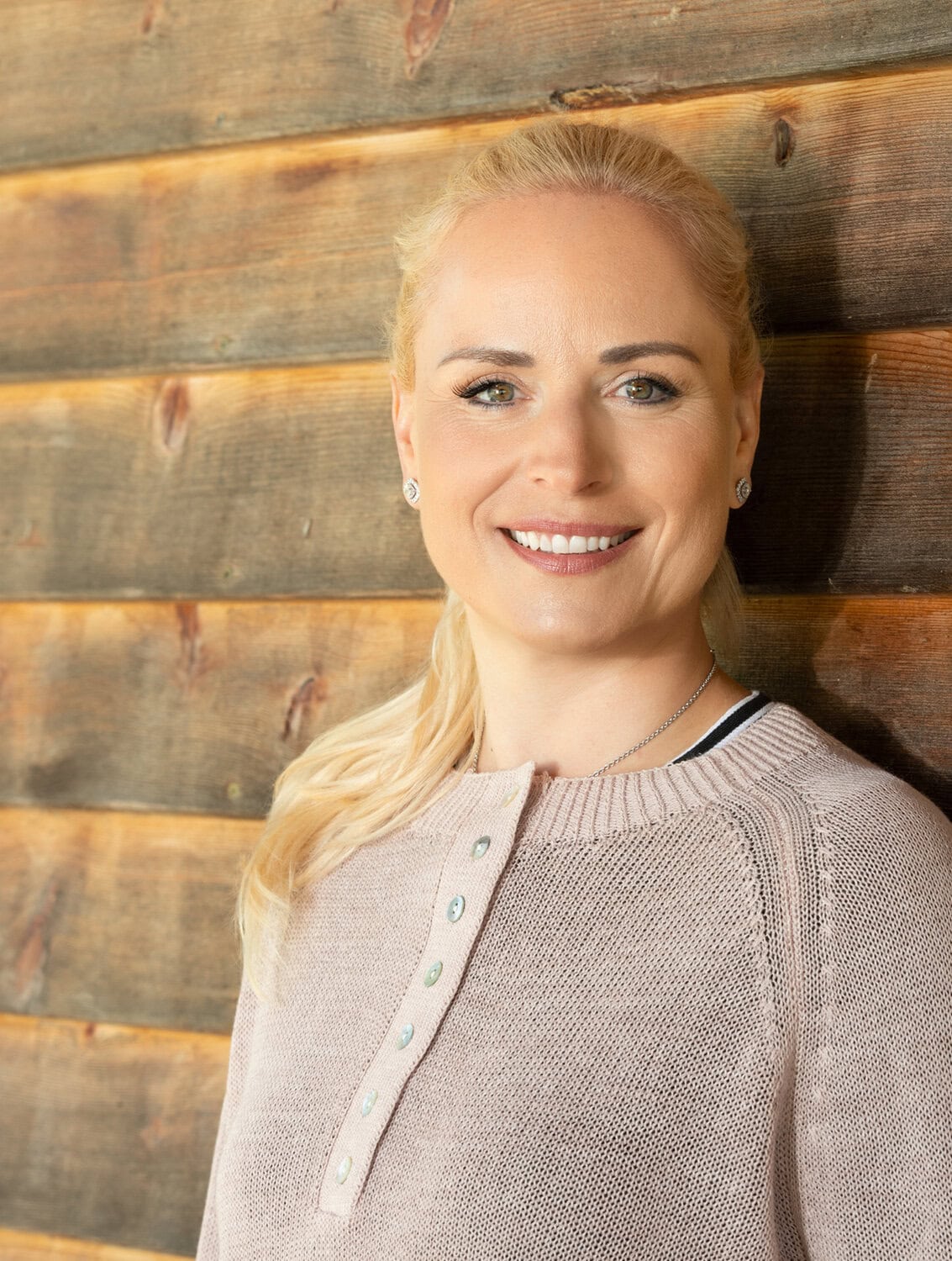 Selbstbewusste Frau vor Holzwand, Business Coaching, berufliche Neuorientierung.