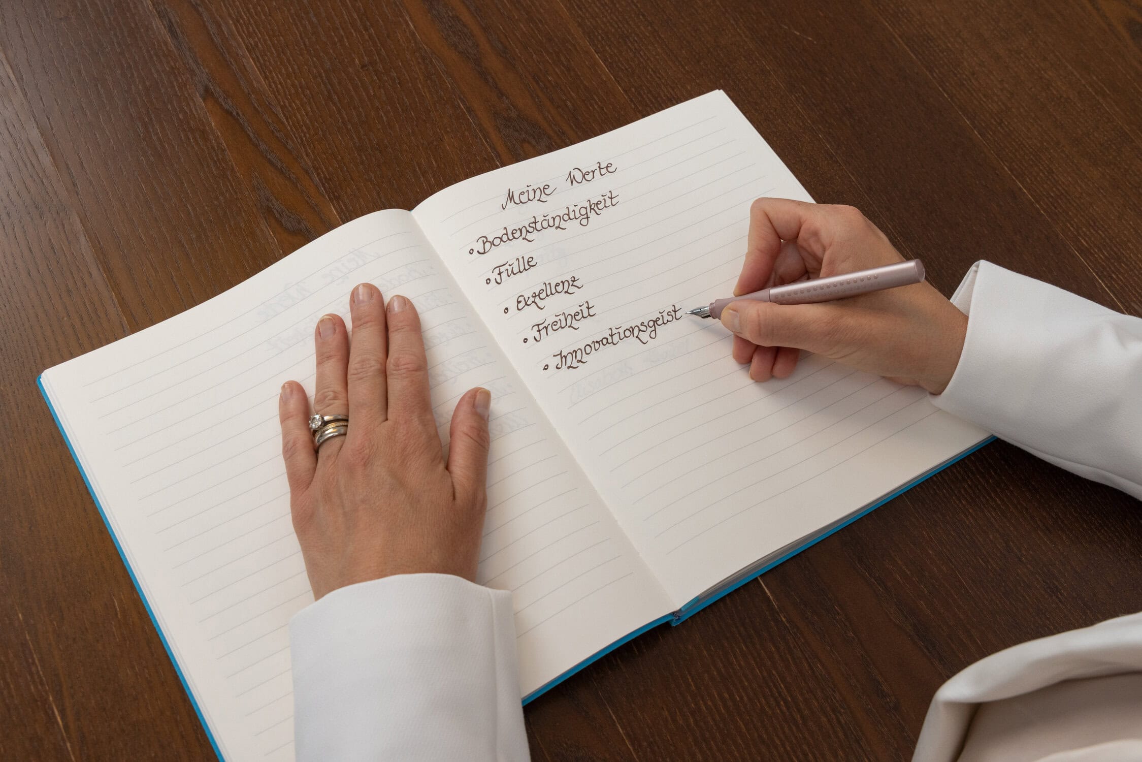 Person schreibt in Notizbuch mit Stichpunkten zu persönlichen Eigenschaften.